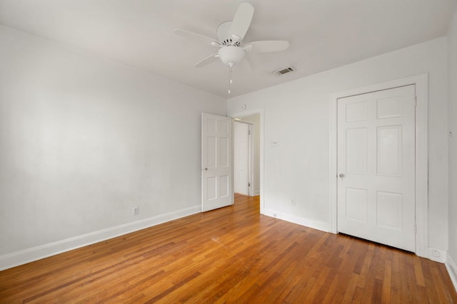 unfurnished bedroom featuring baseboards, a ceiling fan, wood finished floors, and visible vents