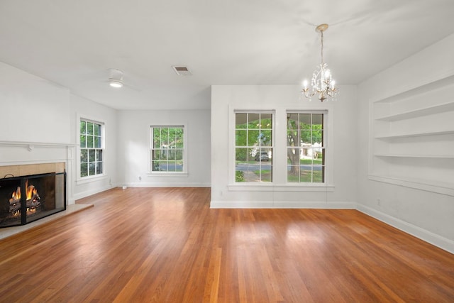 unfurnished living room with wood finished floors, visible vents, built in features, and baseboards