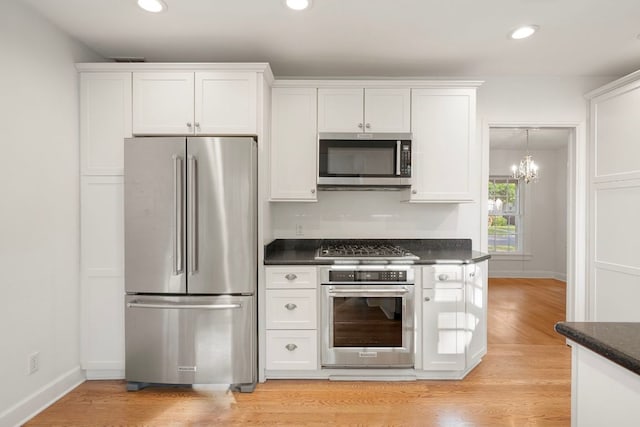 kitchen featuring dark countertops, appliances with stainless steel finishes, white cabinetry, and light wood-type flooring