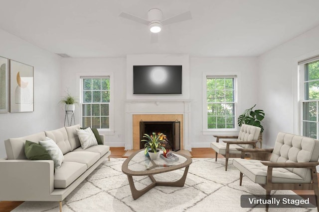 living area with a fireplace, wood finished floors, and ceiling fan