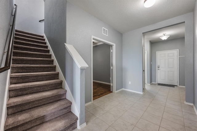 713 Hummingbird Ln, Leander, TX 78641 - stairs featuring tile patterned floors and a textured ceiling