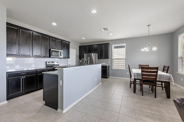 713 Hummingbird Ln, Leander, TX 78641 - kitchen with appliances with stainless steel finishes, light stone counters, a chandelier, an island with sink, and pendant lighting