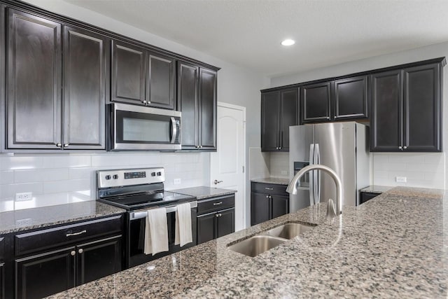 713 Hummingbird Ln, Leander, TX 78641 - kitchen featuring appliances with stainless steel finishes, stone countertops, tasteful backsplash, recessed lighting, and dark cabinetry
