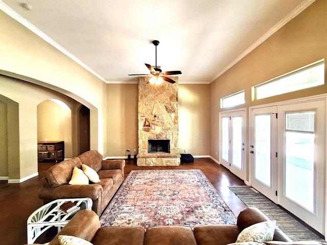 living area featuring a ceiling fan, wood finished floors, arched walkways, and crown molding