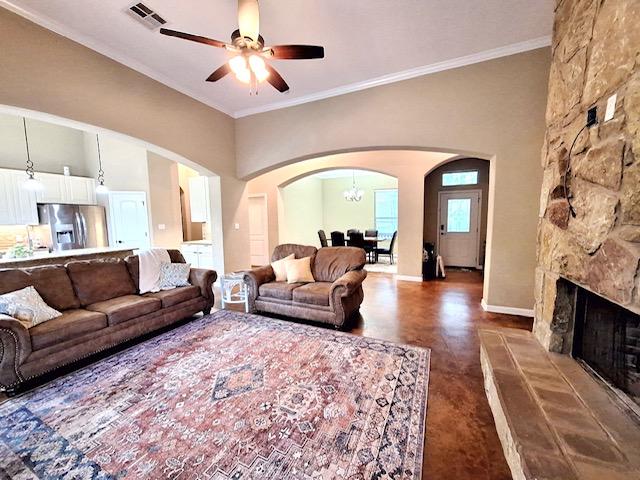 192 W Kaanapali Ln, Bastrop, TX 78602 - living room featuring arched walkways, a ceiling fan, ornamental molding, baseboards, and a fireplace