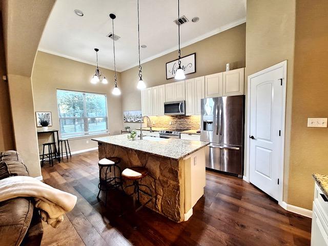 192 W Kaanapali Ln, Bastrop, TX 78602 - kitchen featuring stainless steel appliances, baseboards, decorative backsplash, dark wood finished floors, and ornamental molding