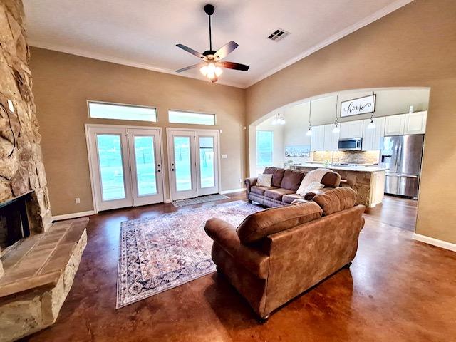 living area featuring baseboards, visible vents, a ceiling fan, concrete floors, and a fireplace