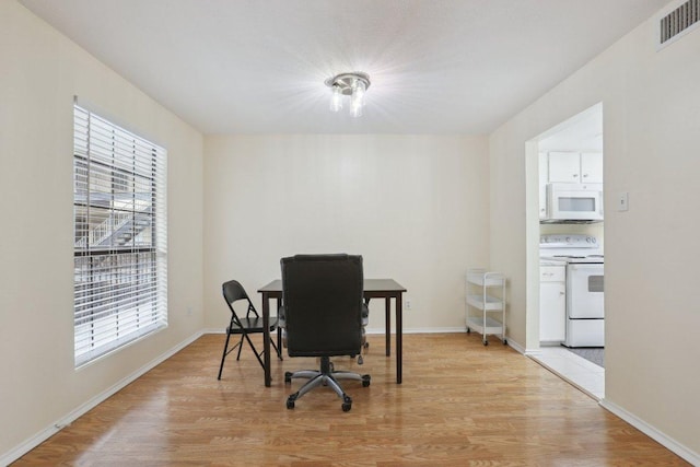 office space with a healthy amount of sunlight, baseboards, light wood finished floors, and visible vents