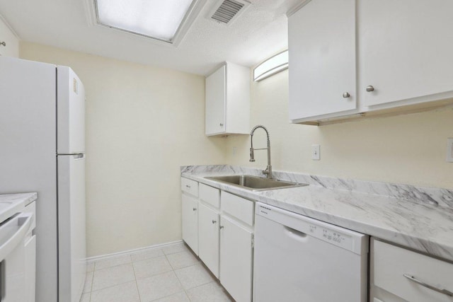 kitchen featuring visible vents, white appliances, light countertops, white cabinets, and a sink