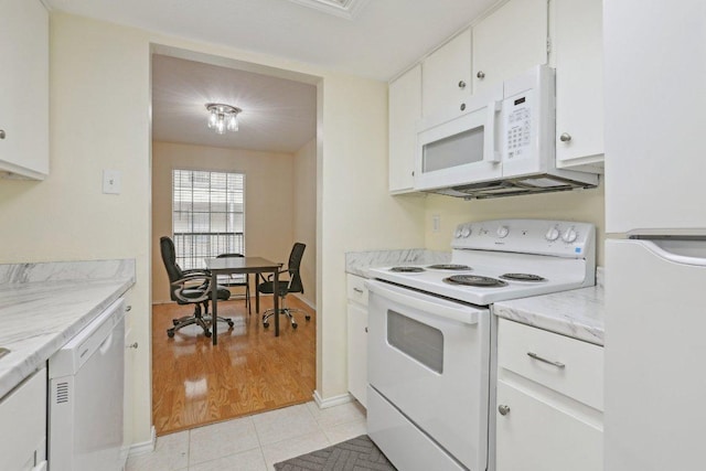 kitchen featuring baseboards, light tile patterned floors, white cabinets, and white appliances