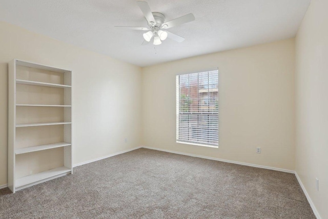 empty room with carpet floors, baseboards, and a ceiling fan