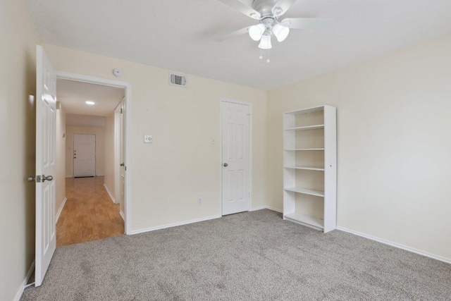 unfurnished bedroom with baseboards, carpet flooring, a ceiling fan, and visible vents