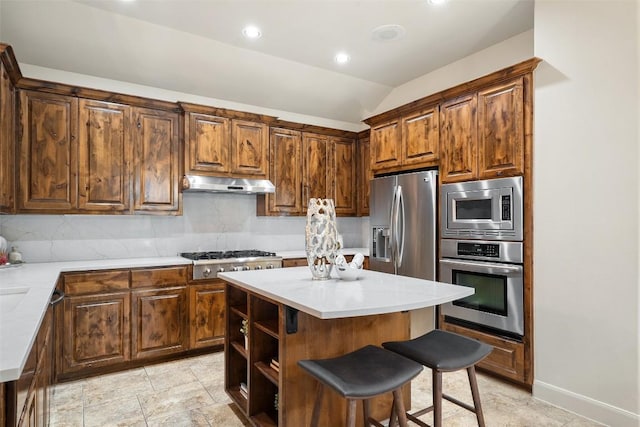 13606 Montview Dr, Austin, TX 78732 - kitchen with appliances with stainless steel finishes, under cabinet range hood, a kitchen breakfast bar, vaulted ceiling, and a center island