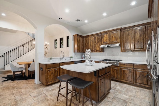 13606 Montview Dr, Austin, TX 78732 - kitchen with under cabinet range hood, a center island, arched walkways, a breakfast bar area, and light countertops