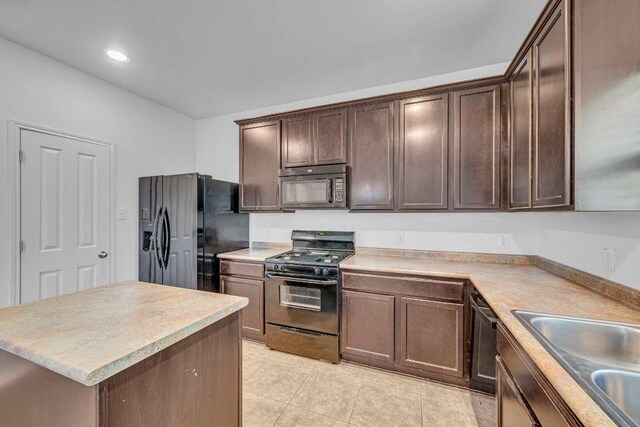 1013 Hondo Ln, Hutto, TX 78634 - kitchen featuring dark brown cabinets, a sink, light countertops, black appliances, and light tile patterned flooring
