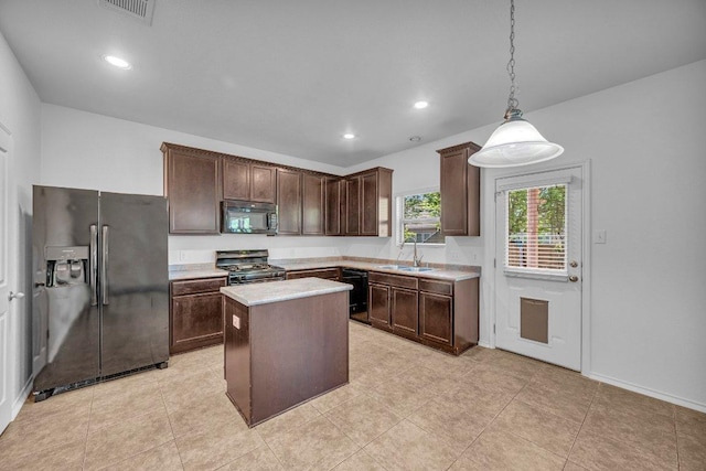 kitchen featuring dark brown cabinetry, a sink, a kitchen island, visible vents, and black appliances