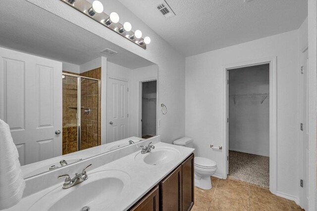 1013 Hondo Ln, Hutto, TX 78634 - bathroom with toilet, a textured ceiling, tiled shower, and a sink