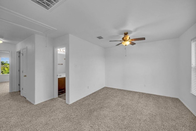 empty room featuring a ceiling fan, visible vents, light carpet, and attic access