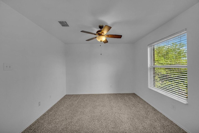 carpeted spare room featuring baseboards, ceiling fan, and visible vents