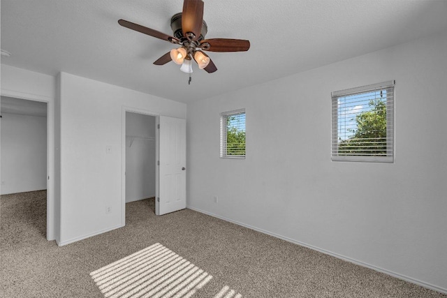 unfurnished bedroom featuring ceiling fan, carpet floors, baseboards, a spacious closet, and a closet