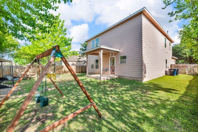 back of house with a ceiling fan, a patio area, a fenced backyard, a playground, and a yard