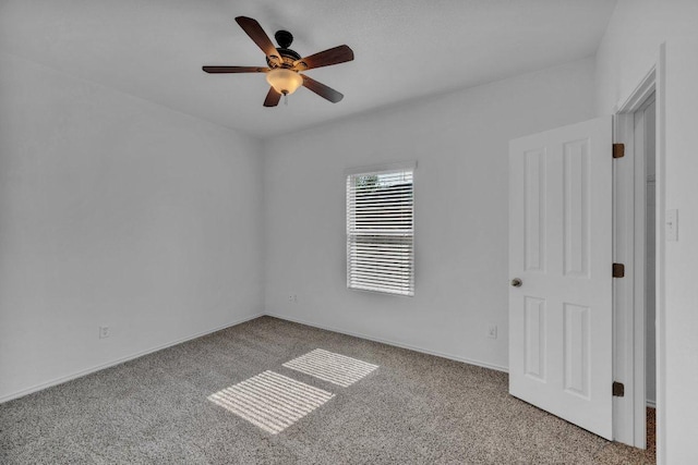 carpeted empty room featuring a ceiling fan and baseboards