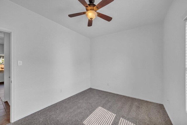 unfurnished room featuring baseboards, carpet flooring, and a ceiling fan