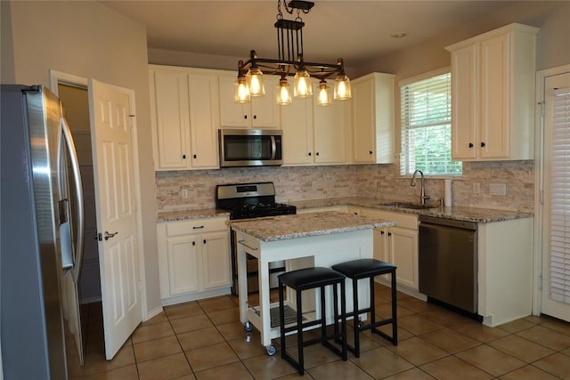 kitchen with white cabinets, stainless steel appliances, a sink, and backsplash