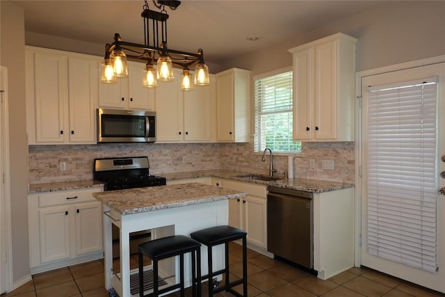 kitchen featuring white cabinets, tile patterned floors, a sink, tasteful backsplash, and appliances with stainless steel finishes