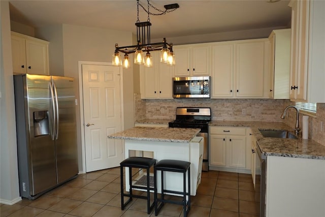 kitchen with tile patterned flooring, backsplash, appliances with stainless steel finishes, and a sink
