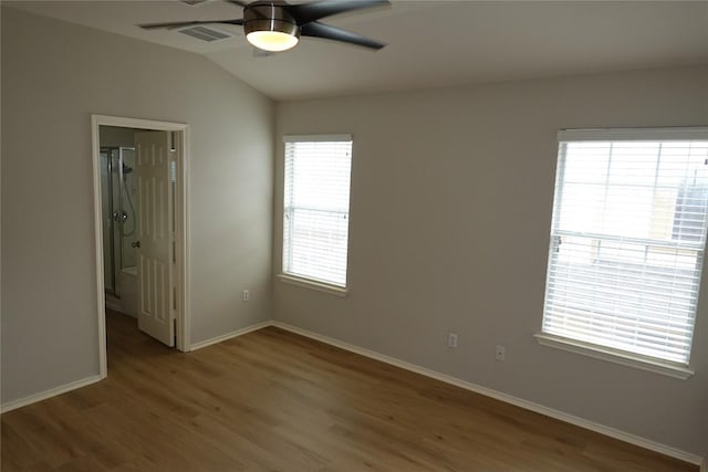 unfurnished bedroom with vaulted ceiling, wood finished floors, ceiling fan, baseboards, and visible vents