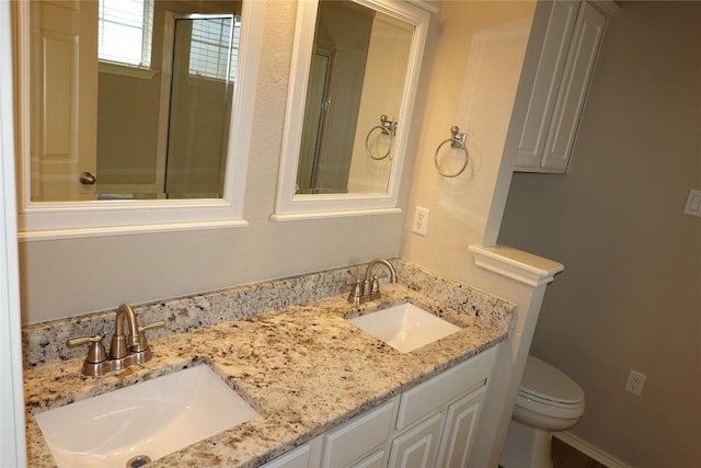 bathroom featuring a sink, double vanity, and toilet