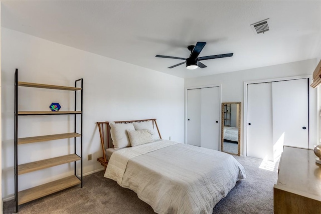 carpeted bedroom with multiple closets, visible vents, and a ceiling fan