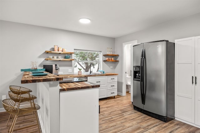 12099 Bonham Ranch Rd, Dripping Springs, TX 78620 - kitchen featuring butcher block countertops, stainless steel fridge, open shelves, white cabinetry, and light wood-style flooring