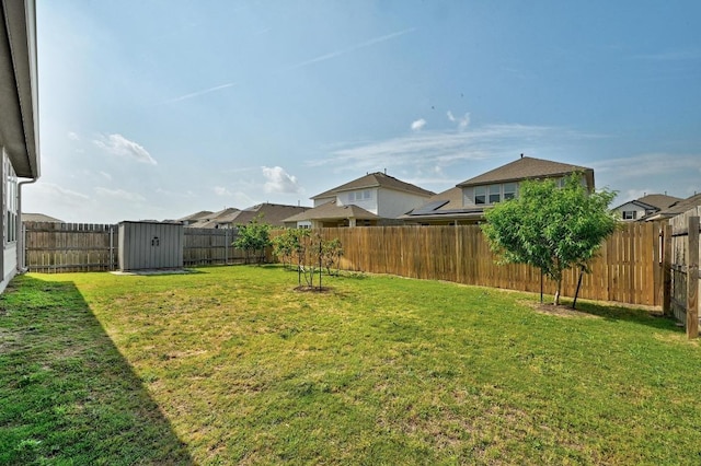 view of yard with a storage unit, a fenced backyard, and an outbuilding