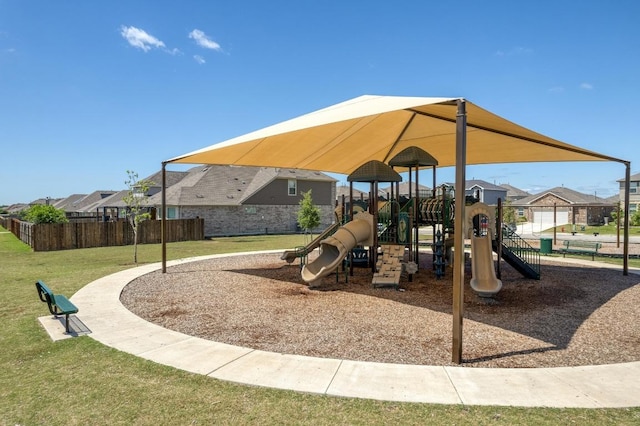 community playground featuring fence, a residential view, and a lawn
