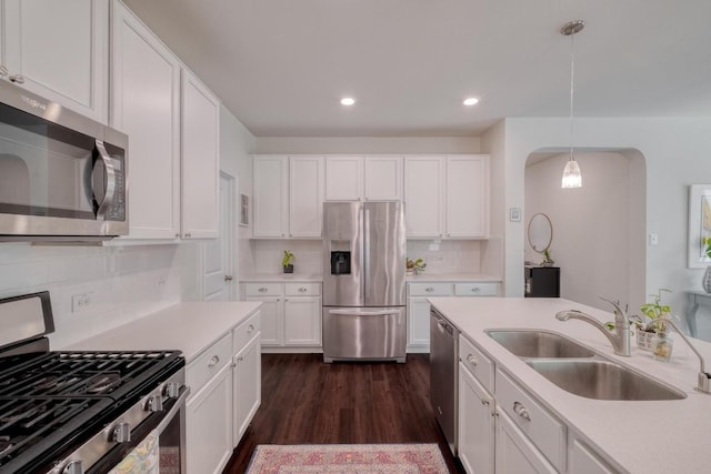 kitchen featuring appliances with stainless steel finishes, a sink, tasteful backsplash, light countertops, and white cabinetry