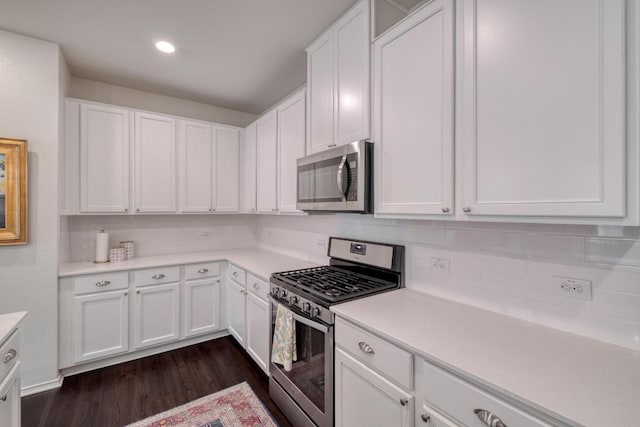 kitchen featuring stainless steel appliances, white cabinetry, dark wood-type flooring, tasteful backsplash, and light countertops