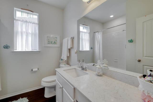 bathroom featuring healthy amount of natural light, toilet, wood finished floors, and baseboards