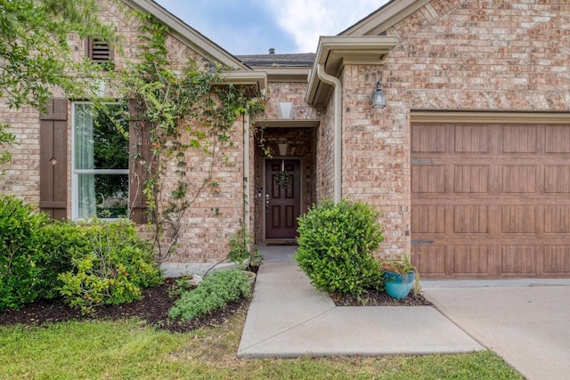 doorway to property with an attached garage and brick siding