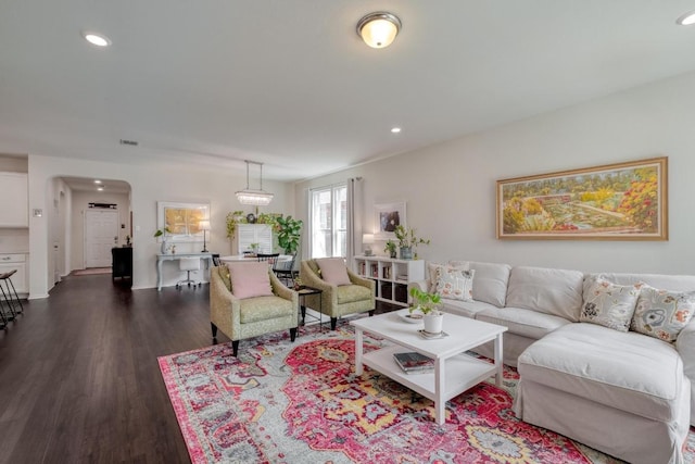 living area featuring dark wood finished floors, recessed lighting, and arched walkways