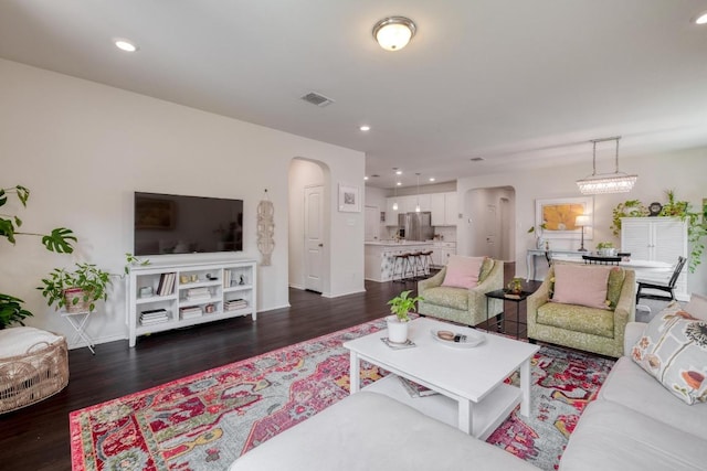 living area featuring arched walkways, wood finished floors, baseboards, and recessed lighting