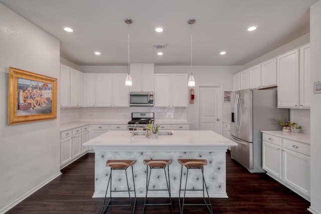 kitchen featuring appliances with stainless steel finishes, a breakfast bar area, an island with sink, light countertops, and recessed lighting