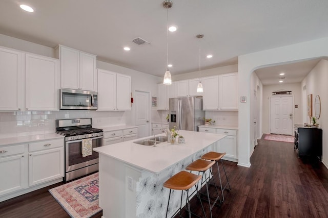 kitchen with stainless steel appliances, a sink, decorative backsplash, white cabinets, and recessed lighting