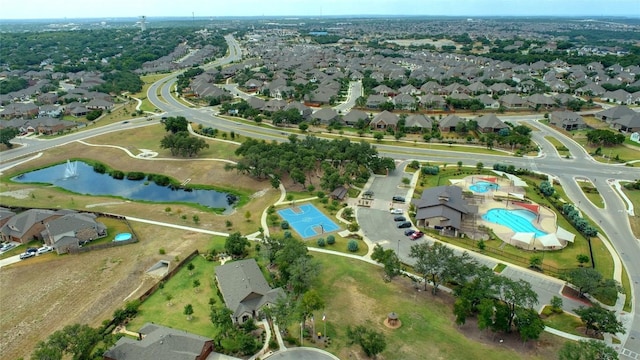 aerial view of property and surrounding area featuring a large body of water, a pool, and nearby suburban area