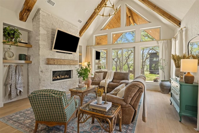 living area featuring high vaulted ceiling, light wood finished floors, a fireplace, beam ceiling, and visible vents