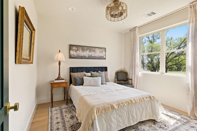 bedroom with light wood-style floors, visible vents, and baseboards