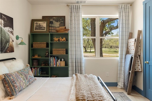 bedroom featuring baseboards, wood finished floors, and visible vents