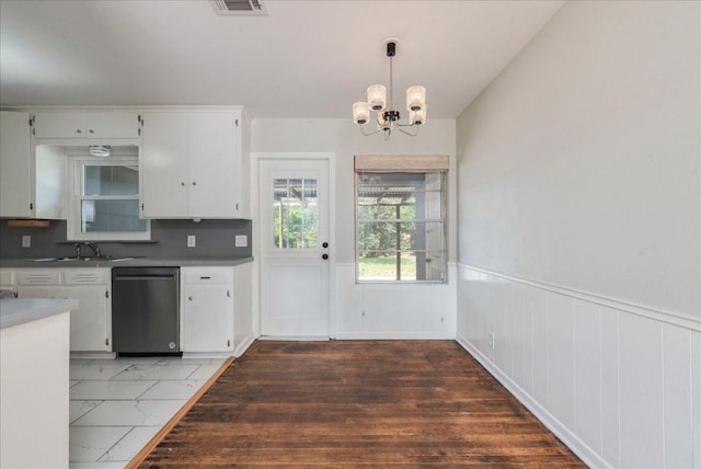 kitchen featuring white cabinets, dishwashing machine, a wainscoted wall, and an inviting chandelier