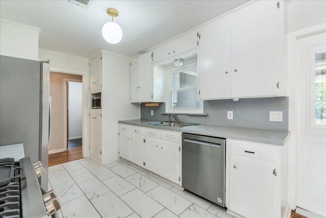 kitchen featuring marble finish floor, white cabinets, appliances with stainless steel finishes, and a sink